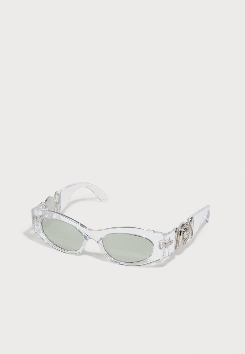 Ochelari de soare din plastic transparent cu lentile ovale verzi, având accesorii din metal argintiu pe brațe și un design elegant.