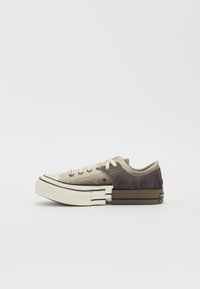 Zapatillas bajas con una parte superior de cuero beige y marrón, secciones texturizadas, acentos en crema, cordones planos y una suela gruesa y con patrón.