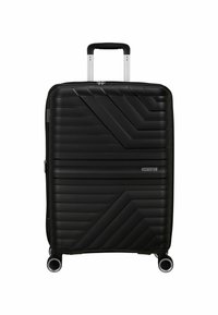 Valigia rigida nera con design a coste diagonali texturizzate, manico retrattile e quattro ruote girevoli. Presente logo del marchio.