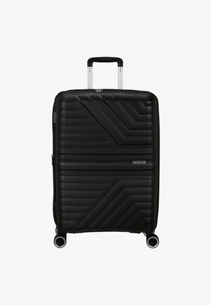 Valigia rigida nera con design a coste diagonali texturizzate, manico retrattile e quattro ruote girevoli. Presente logo del marchio.