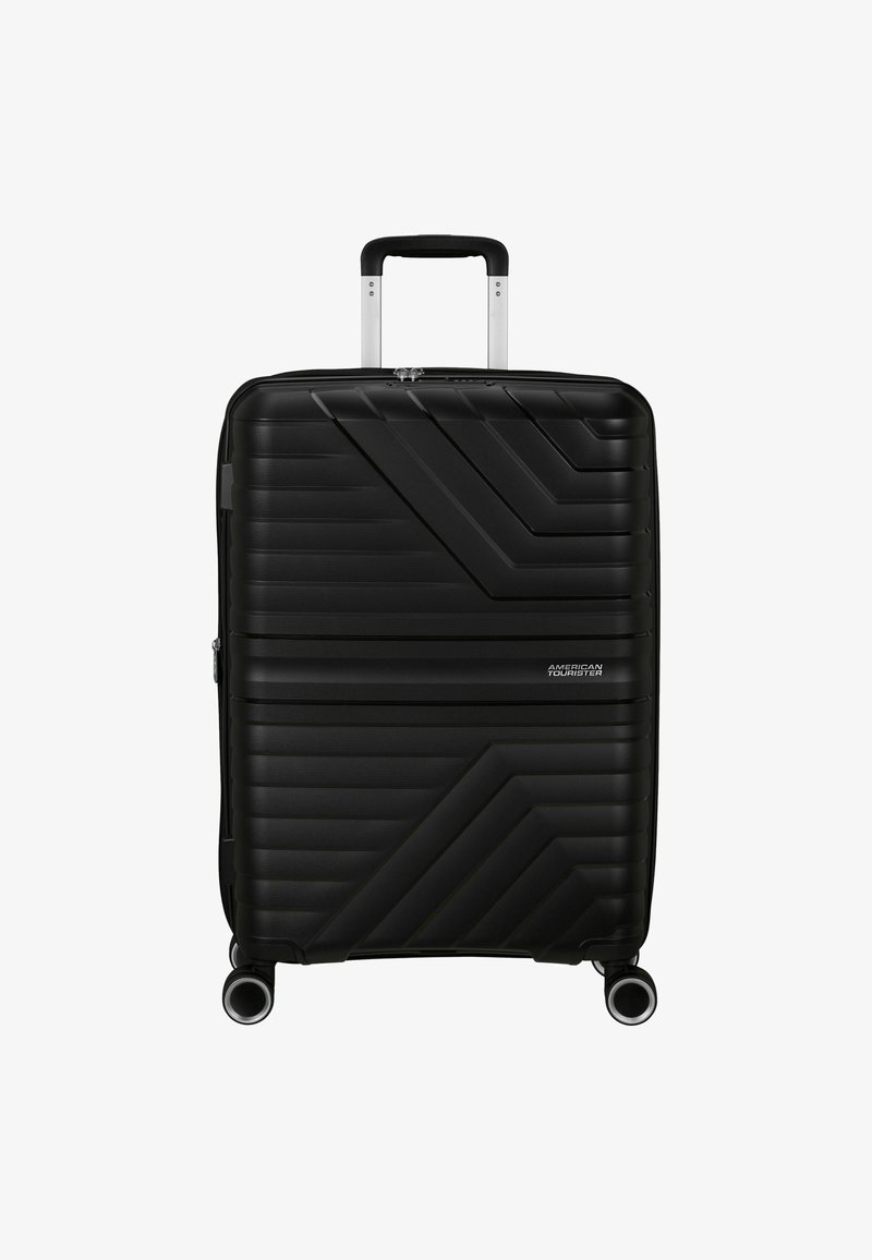 Valigia rigida nera con design a coste diagonali texturizzate, manico retrattile e quattro ruote girevoli. Presente logo del marchio.