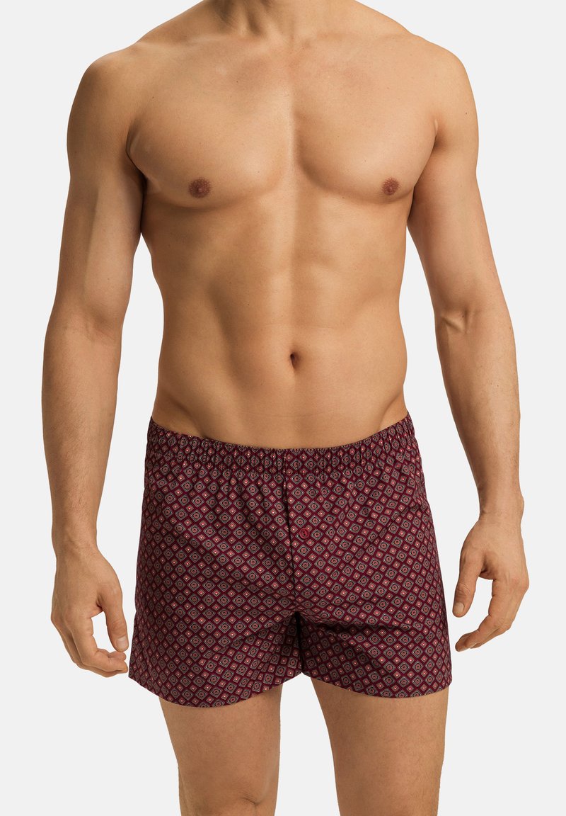Boxers à motif rouge et marine avec une ceinture élastique, présentant un design géométrique sur un tissu doux. Coupe simple et décontractée.