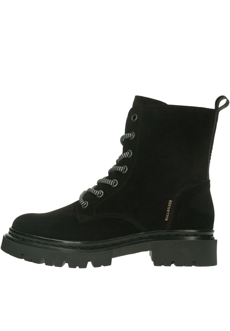 Stivaletto alla caviglia in suede nero con punta tondeggiante, lacci in contrasto bianco e nero, suola in gomma spessa e linguetta sul retro per una facile indossabilità.