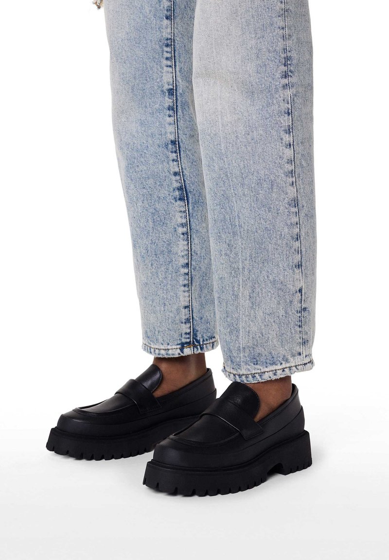 Sorte platform loafers med glat læderfinish og tyk gummisål, kombineret med lyseblå cowboybukser.