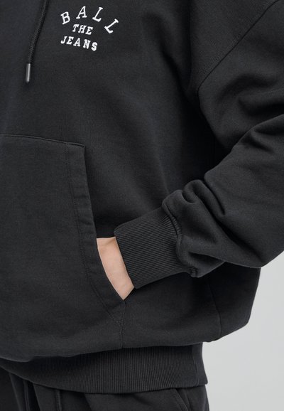 Černá mikina se žebrovanými manžetami a pasem, výbavou v podobě klokaní kapsy a bílého vyšívaného textu "BALL THE JEANS" na hrudi.