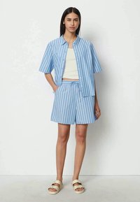 Light blue short-sleeve shirt and matching shorts, both with white vertical stripes. The outfit features a relaxed fit and button closure.