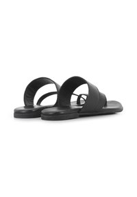 Sandalias de cuero negro con suela plana y dos correas anchas. Presentan un diseño abierto con bordes redondeados y una textura suave.
