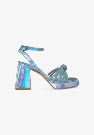 Sandali con tacco alto iridescenti blu, dotati di un ampio tacco a blocco, con una fascia frontale annodata e una sottile cinghia alla caviglia adornata di cristalli.