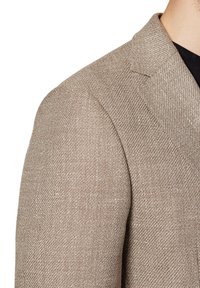 Brązowy żakiet w wzór w jodełkę z teksturowanej tkaniny, ze sztywnymi klapami i dopasowanymi ramionami. Posiada dopasowany krój i subtelne detale.
