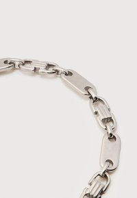 Κοντινή λήψη ασημένιας αλυσίδας περιδέραιου με εναλλασσόμενους ομαλούς ορθογώνιους κρίκους και ραβδωτές οβάλ συνδέσεις πάνω σε λευκό φόντο.