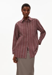 Maroon striped shirt with white vertical lines, long sleeves, button-down front, and a chest pocket. Cotton fabric, relaxed fit.