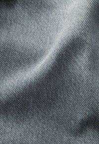 Grau jeansstoff mit einer glatten Textur, die ein feines Gewebemuster und einen leichten Glanz zeigt, was auf ein hochwertiges Material hinweist.