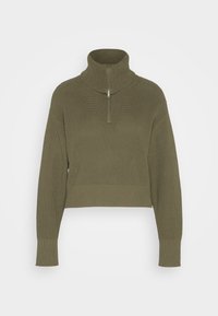 Pull court vert olive avec col montant, présentant une fermeture éclair frontale à moitié et une texture côtelée sur le corps et les manches.