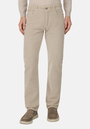 Beige corduroy broek met rechte pijpen, voorzien van zijzakken en een enkele knoopsluiting in de taille, gecombineerd met bruine instappers.