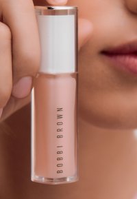 Bobbi Brown lipgloss in een doorzichtig tube met een witte dop. De gloss heeft een zachte roze tint en een glanzende afwerking.