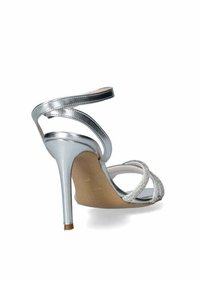 Sandal con tacco a stiletto argento, caratterizzato da molteplici cinture sottili e un dettaglio texturizzato con strass. Scollo aperto sul retro e interno liscio.