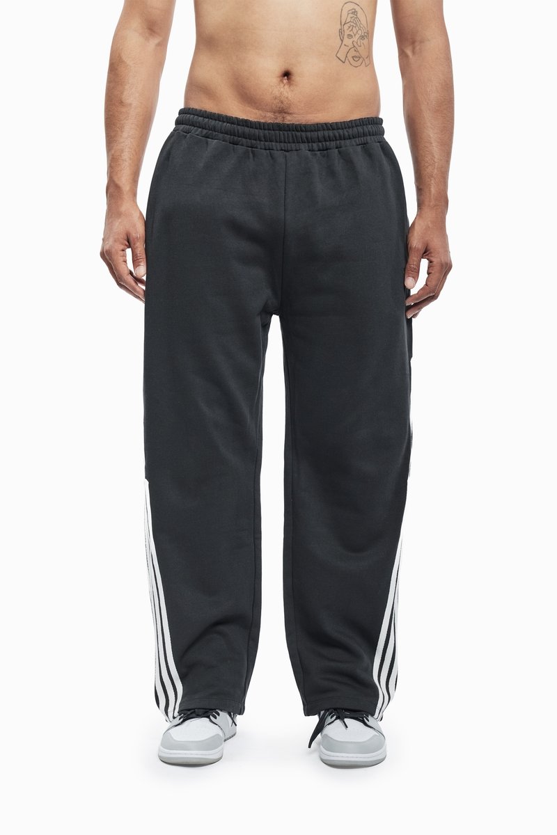 Black sweatpants with white stripe accents on the sides, featuring an elastic waistband and a relaxed fit. Made of soft, comfortable material.