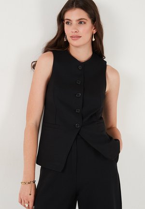 Black sleeveless waistcoat with a high neckline, featuring a button placket, two side pockets, and a fitted design.