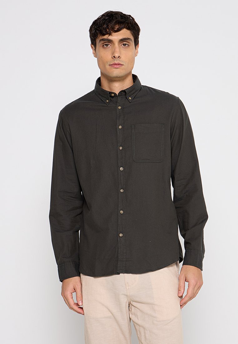 Camisa de botón de manga larga de color verde oscuro con un bolsillo en el pecho, botones de color beige y un cuello con solapa. Hecha de tela de algodón texturizada.