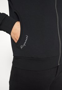 Czarna rozpinana bluza z kapturem wykonana z bawełnianej mieszanki, z przednią kieszenią, ściągaczami na rękawach i dole, oraz haftowanym logo po lewej stronie.
