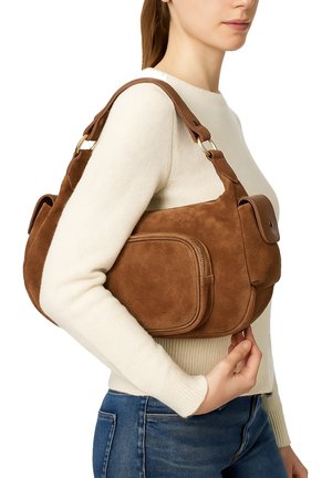 Sac à main en daim marron avec une forme courbée, une bandoulière amovible et deux poches avant. Accents en matériel doré. Texture douce.