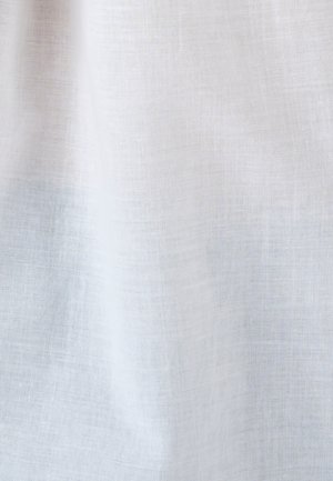 Tessuto bianco leggero e semi-trasparente con trama aperta, appeso con pieghe morbide e dettagli di trama visibili.