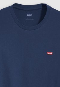 Tricou din bumbac bleu închis cu decolteu rotund și mâneci scurte. Are un mic logo Levi's roșu în zona stângă a pieptului.