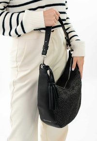 Bolso de mano de cuero negro con detalle tejido texturizado, apertura con cremallera y correa desmontable. Decorado con un fleco y un logotipo.