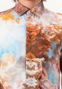 Hemd mit Knopfleiste, das ein lebendiges, bedrucktes Design mit klassischen Motiven in Orangetönen, Blau und Braun zeigt, gefertigt aus leichtem Stoff.