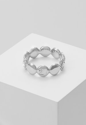 Silbernes rundes Perlen-Stretcharmband mit einem Schwanenemblem auf einer Perle, präsentiert auf einem weißen Podest vor einem hellgrauen Hintergrund.