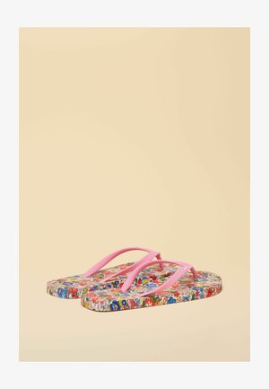 Șlapi cu bretele roz și tălpi cu model floral în roșu, albastru, verde și alb pe un fundal bej.