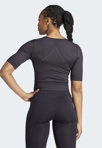 Top athletic negru cu mânecă scurtă, având un design fit, textură netedă și un detaliu de cusătură triunghiulară la spate.