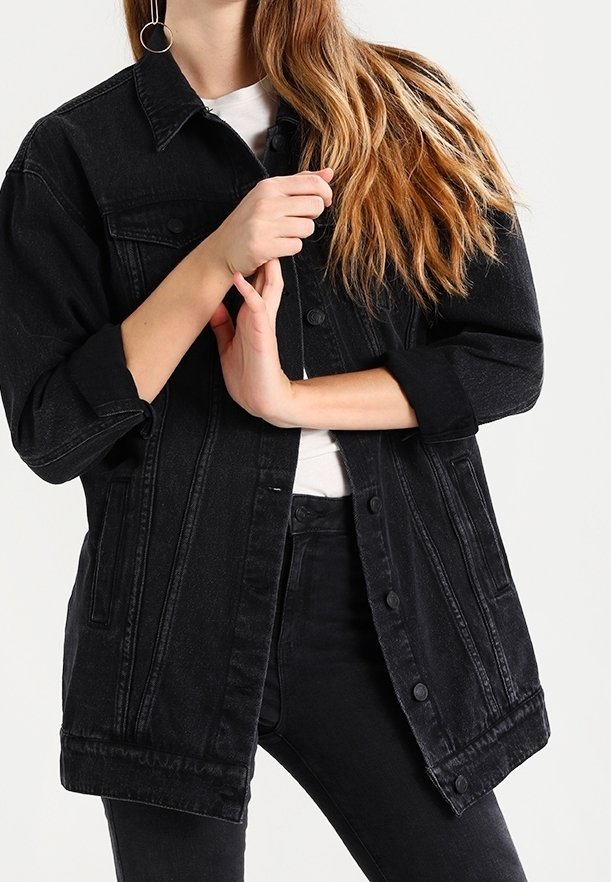 Svart denimjacka med knäppning framtill, sidofickor och uppvikta ärmar. Har en klassisk krage och en något oversized passform.