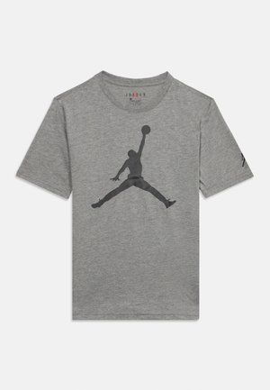 T-shirt gris à manches courtes avec une grande silhouette noire d'un joueur de basket sautant avec un ballon sur le devant.