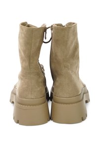 Beige suede ankle boots with a chunky rubber sole, featuring two back zippers and textured upper for added grip.
