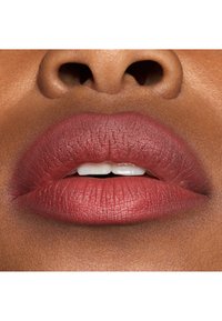 Rouge à lèvres mauve mat sur des lèvres pulpeuses, mettant en valeur les fines lignes et une texture lisse, avec un léger éclat sur la surface intérieure des lèvres.