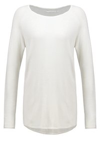 Haut à manches longues en tissu blanc doux, avec un large col rond et un ourlet légèrement arrondi. La texture semble lisse et légère.