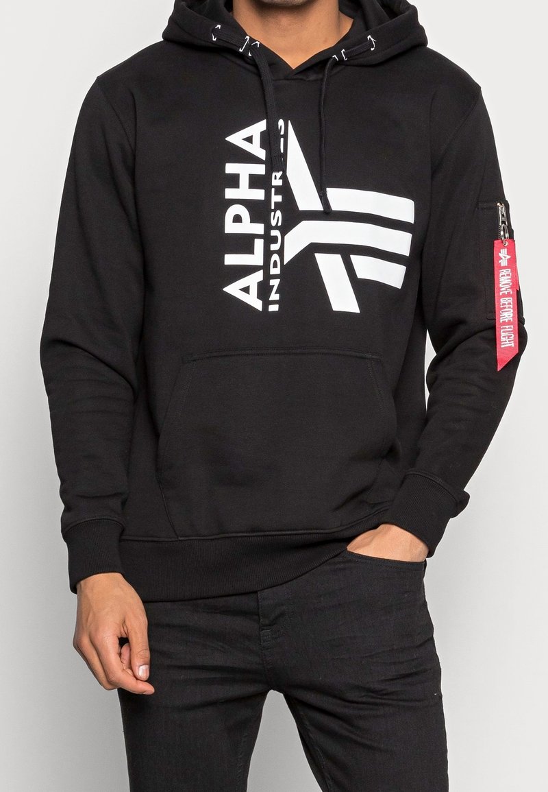 Felpa nera con cappuccio e logo bianco "ALPHA INDUSTRIES", tasca anteriore, cappuccio con cordino regolabile e tasca con zip rossa sul manica.