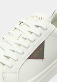 White leather sneaker with white laces, a grey and red triangular logo patch reading "REPLAY," and "REPLAY SINCE 1981" on the tongue.