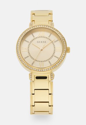 Montre en ton or avec un cadran rond, chiffres romains, cadran texturé et accents en cristal autour de la lunette et du bracelet.