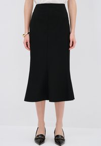 Mustasilkkihame, jossa on levenevä helma, valmistettu sileästä kankaasta. Yhdistetty teräväkärkisiin mustiin kenkiin ja yksinkertaiseen valkoiseen toppiin. Elegantti siluetti.