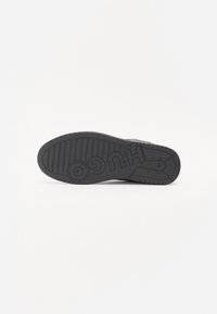 Czarna podeszwa sneakersów z żebrowaną teksturą i okrągłym logo. Posiada płaską podeszwę z wyraźnie wytłoczonym nazwiskiem marki. Okrągły kształt noska.