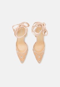 Tacchi a punta nudi con nastri in raso alla caviglia. Presentano un design a rete con piccole strass. Soletta in pelle liscia e parte superiore trasparente.