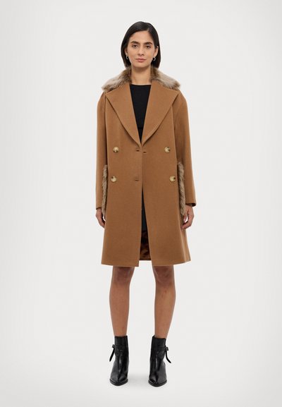 Brauner Wollmantel mit doppelreihigem Design, großem Kragen und Kunstpelz-Akzenten auf den Schultern. Goldfarbene Knöpfe und seitliche Taschen.