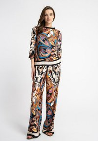 Wielokolorowy, wzorzysty zestaw składający się z luźnej bluzki z rękawami 3/4 oraz spodni z szerokimi nogawkami, wykonany z gładkiego, lekkiego materiału.