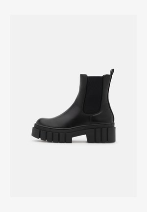 Černá kožená kotníková bota s elastickými bočními panely, robustní podrážkou a poutkem. Disponuje hladkým povrchem a elegantním designem.