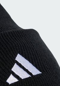 Calzino nero in maglia con un logo a tre righe bianche sul lato. Materiale leggero con una texture a coste per comfort e vestibilità.