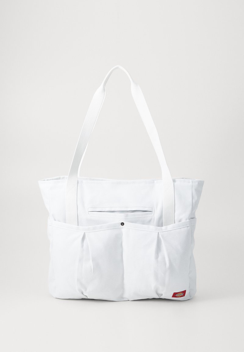 White fabric tote bag with a flat top, two long handles, and an external pocket featuring pleats and a logo. Smooth texture, minimalist design.