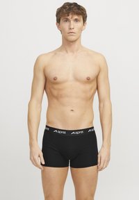 Schwarze Boxershorts aus glattem Stoff mit elastischem Bund, der mit weißem "aprel" Branding versehen ist. Enganliegendes Design und Länge bis zur Mitte des Oberschenkels.