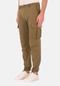 Olijfgroene cargo-broek met meerdere zijzakken, een taps toelopende pasvorm en elastische boorden. Gemaakt van een zachte, duurzame stof.